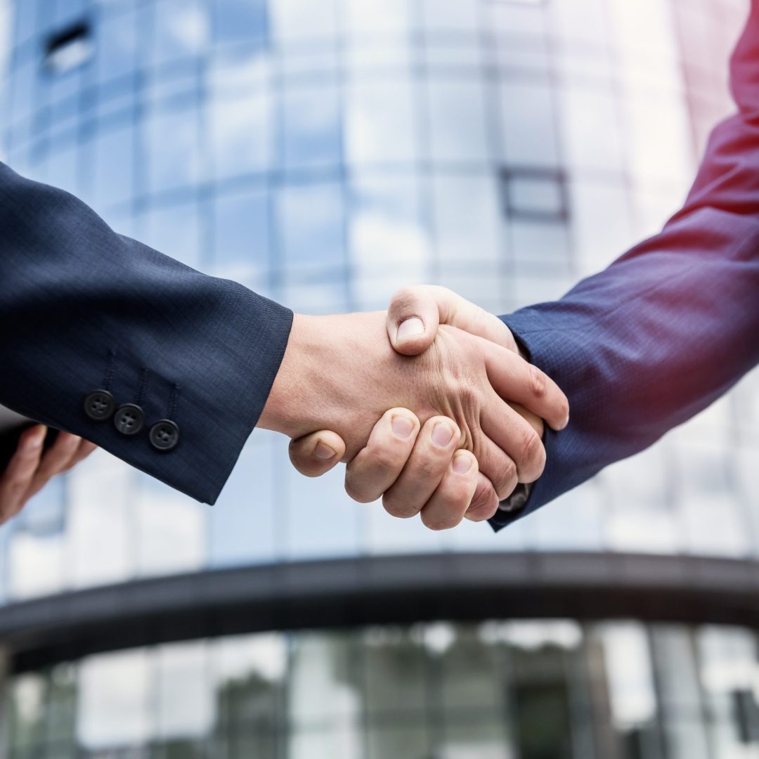 Handshakes against new business center close up